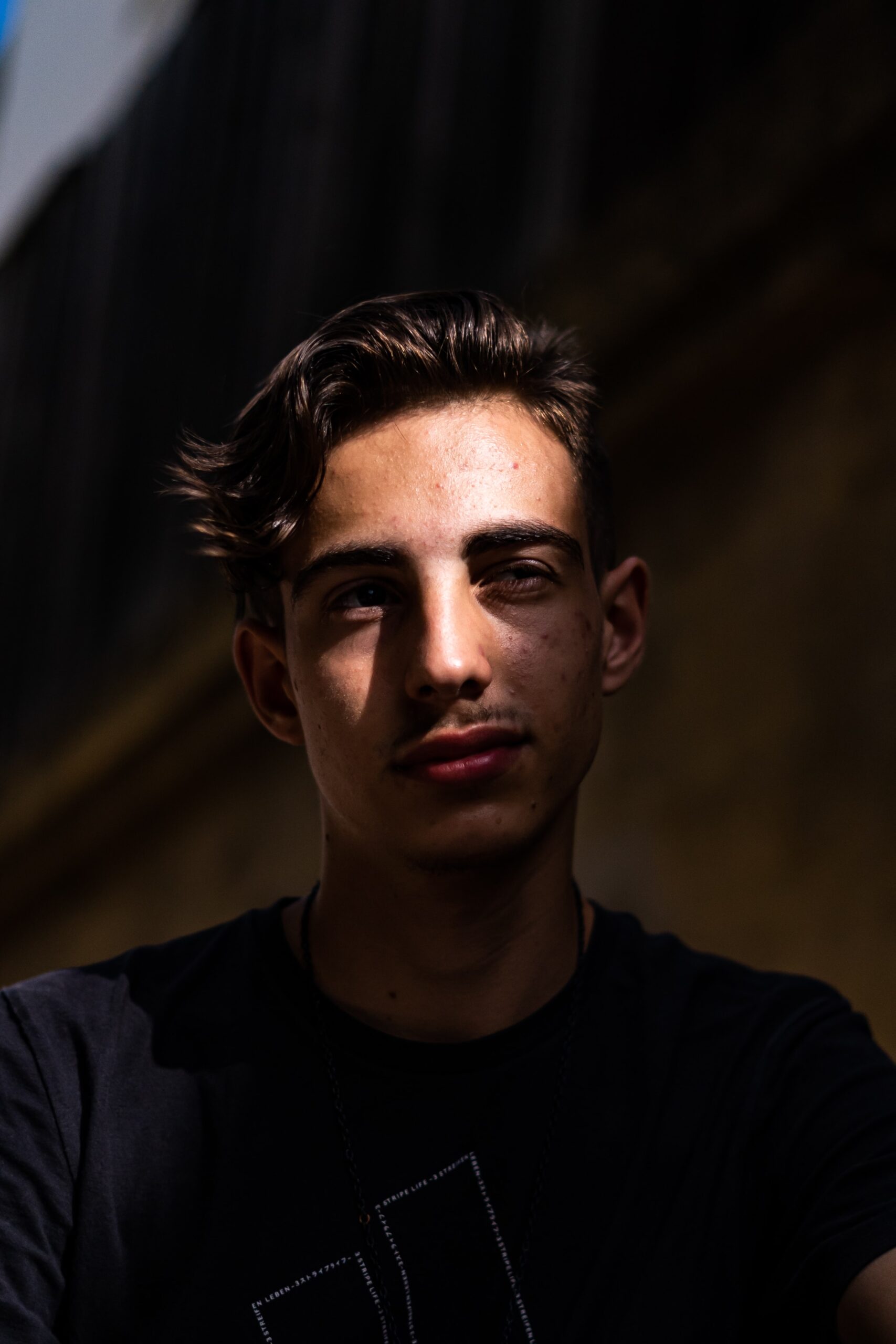 Brown skinned young man looking forlorn with sunrays across his face