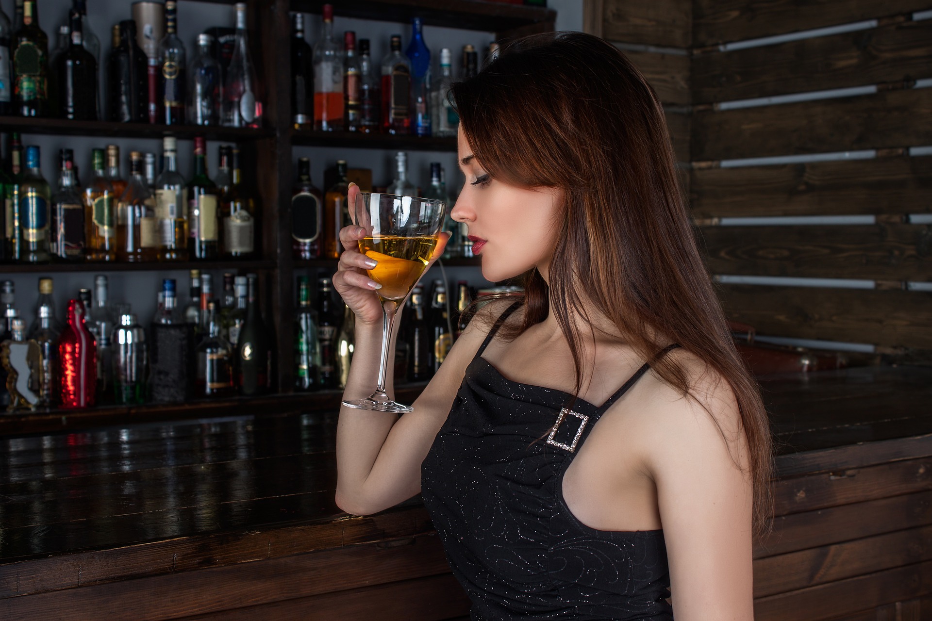 Pretty brunette woman drinking a glass of liquor at a cocktail bar