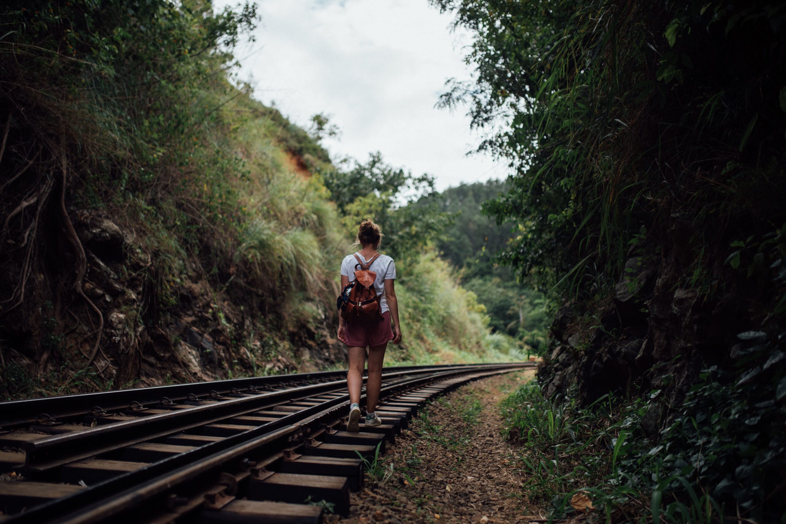 Young woman walking away down a country rail line