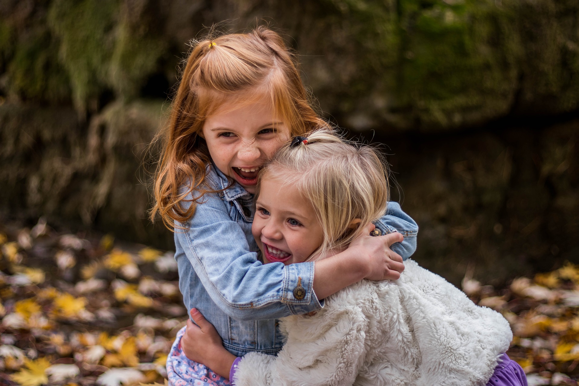 Two young girls to autumnal frocks hugging each other