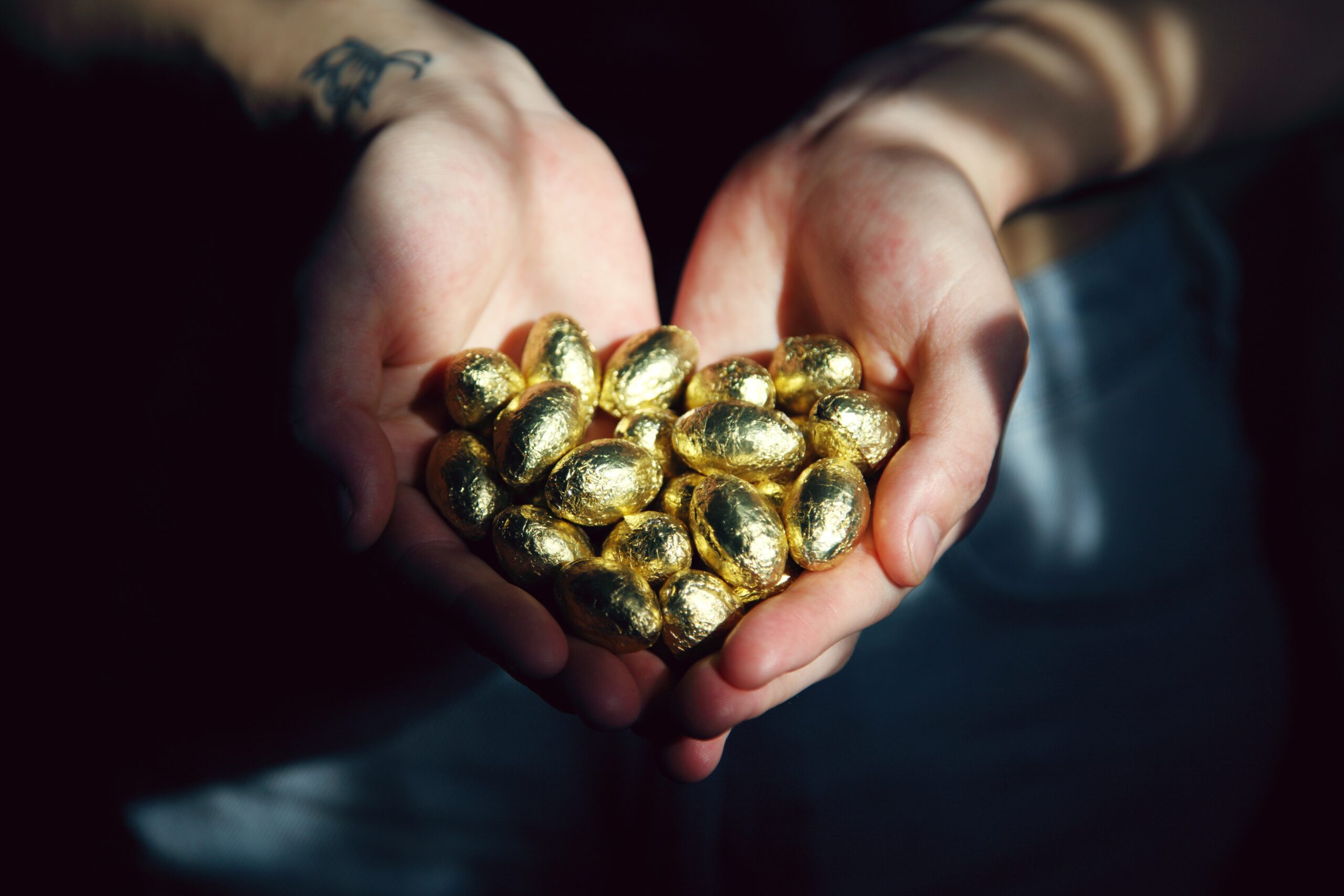 Two hands holding many golden easter eggs