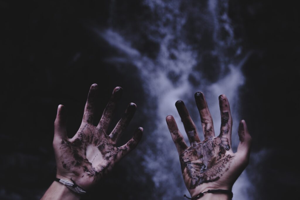 Two muddied hands reaching into the dark sky