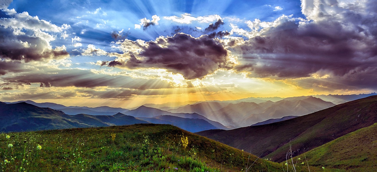 Sunrise of brilliant blue and gold with sun behind a heavy grey cloud