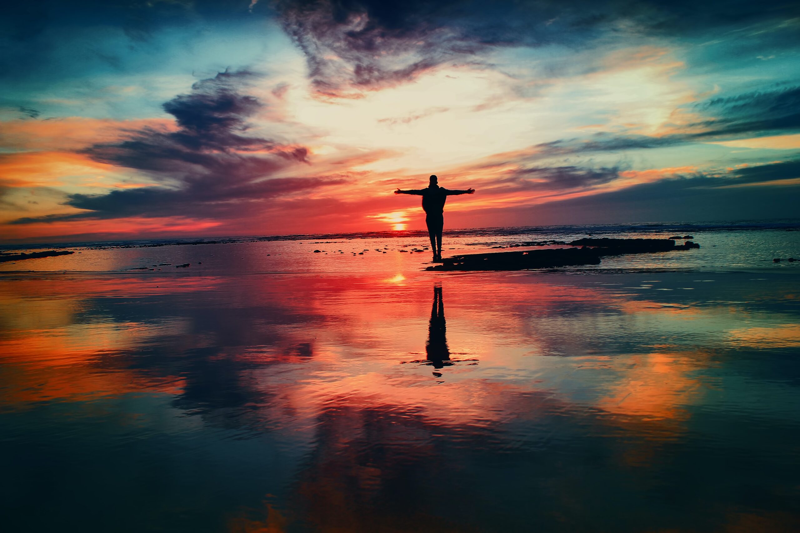 multicoloured scene of man with outstretched arms on a beach
