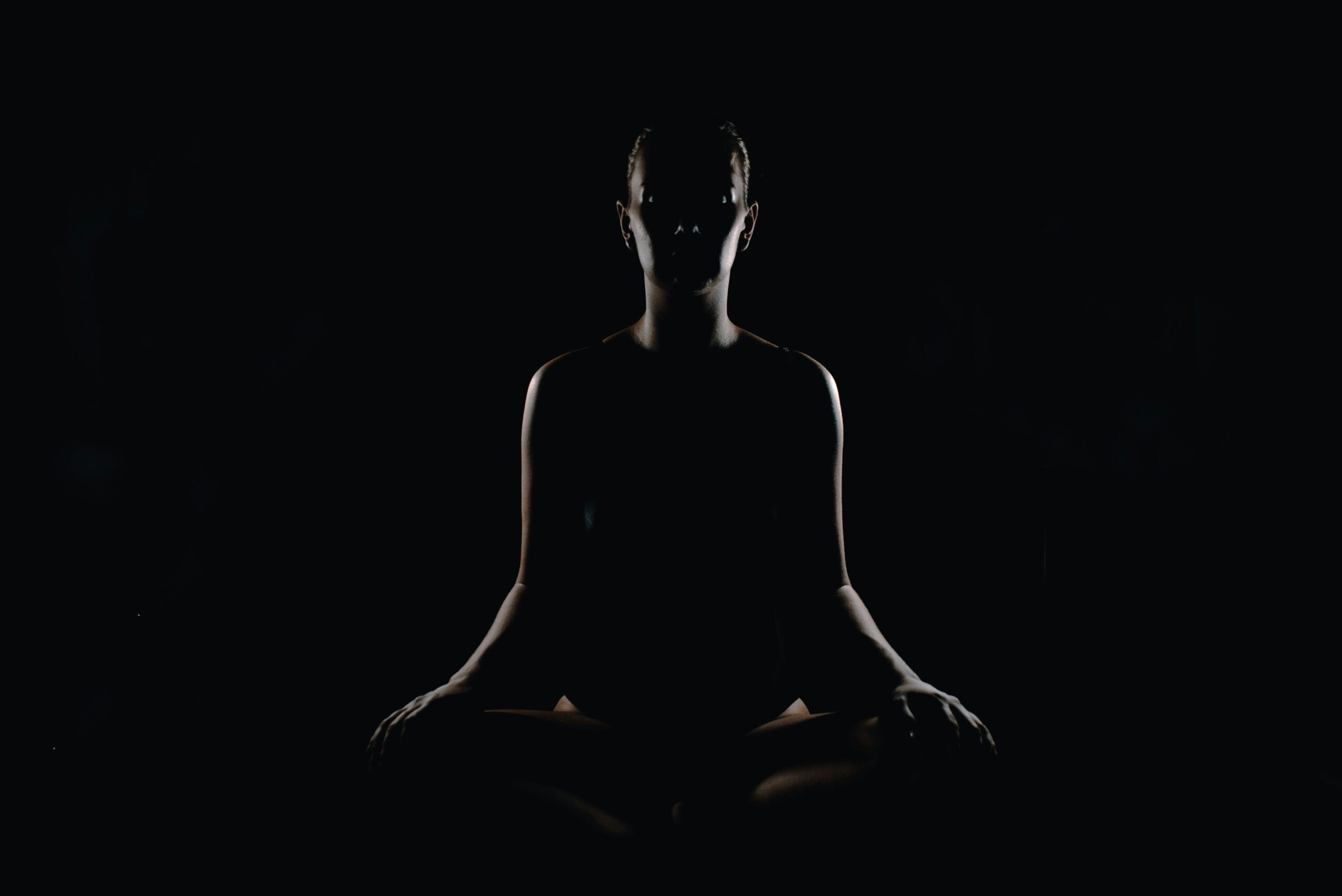 Silhouette of a person meditating cross-legged