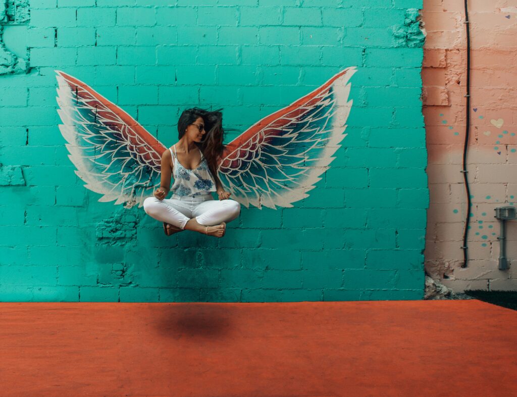 a woman cross-legged and elevating, with wings