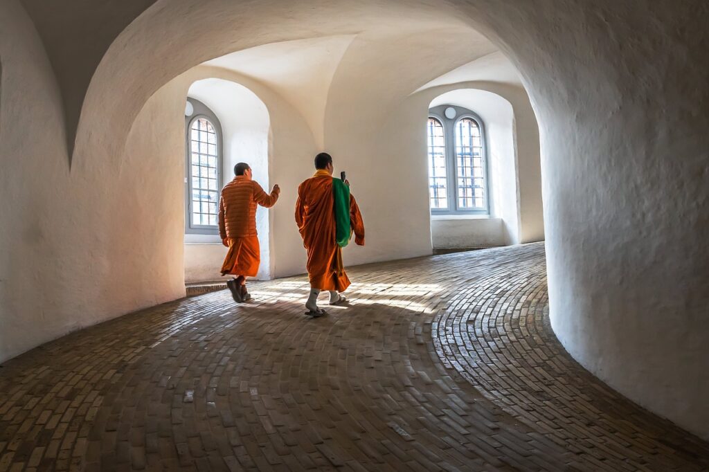 Orange robed monks walking in a spiral corridor