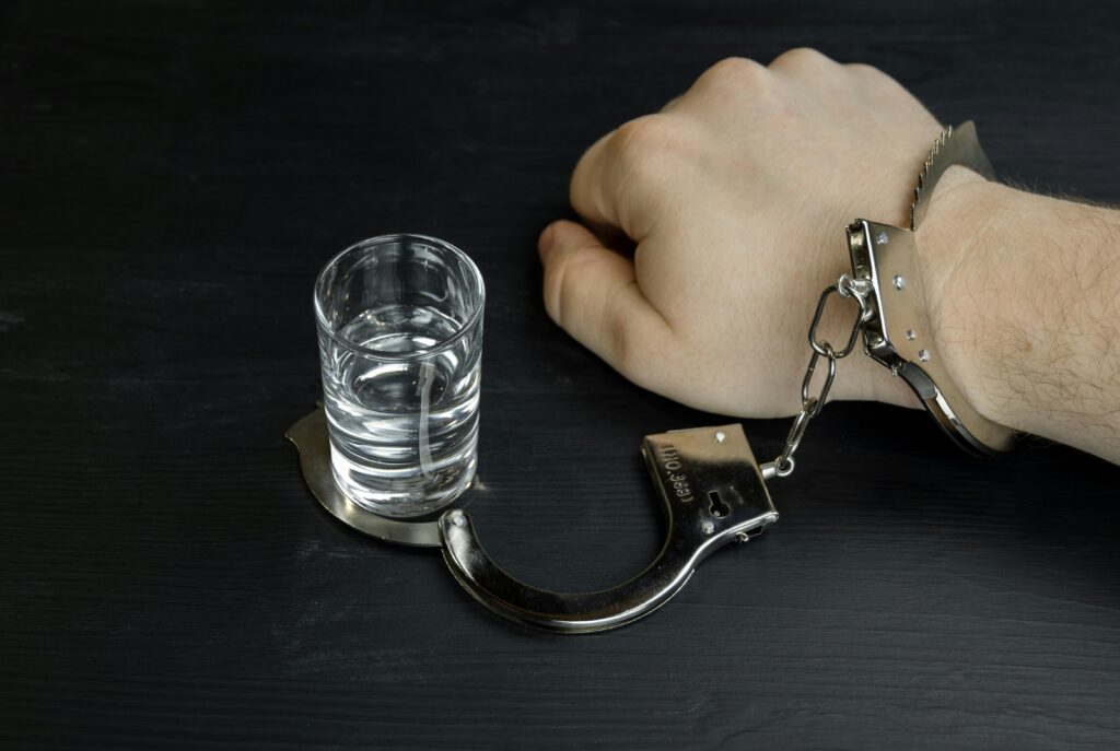 An alcoholic handcuffed to a glass