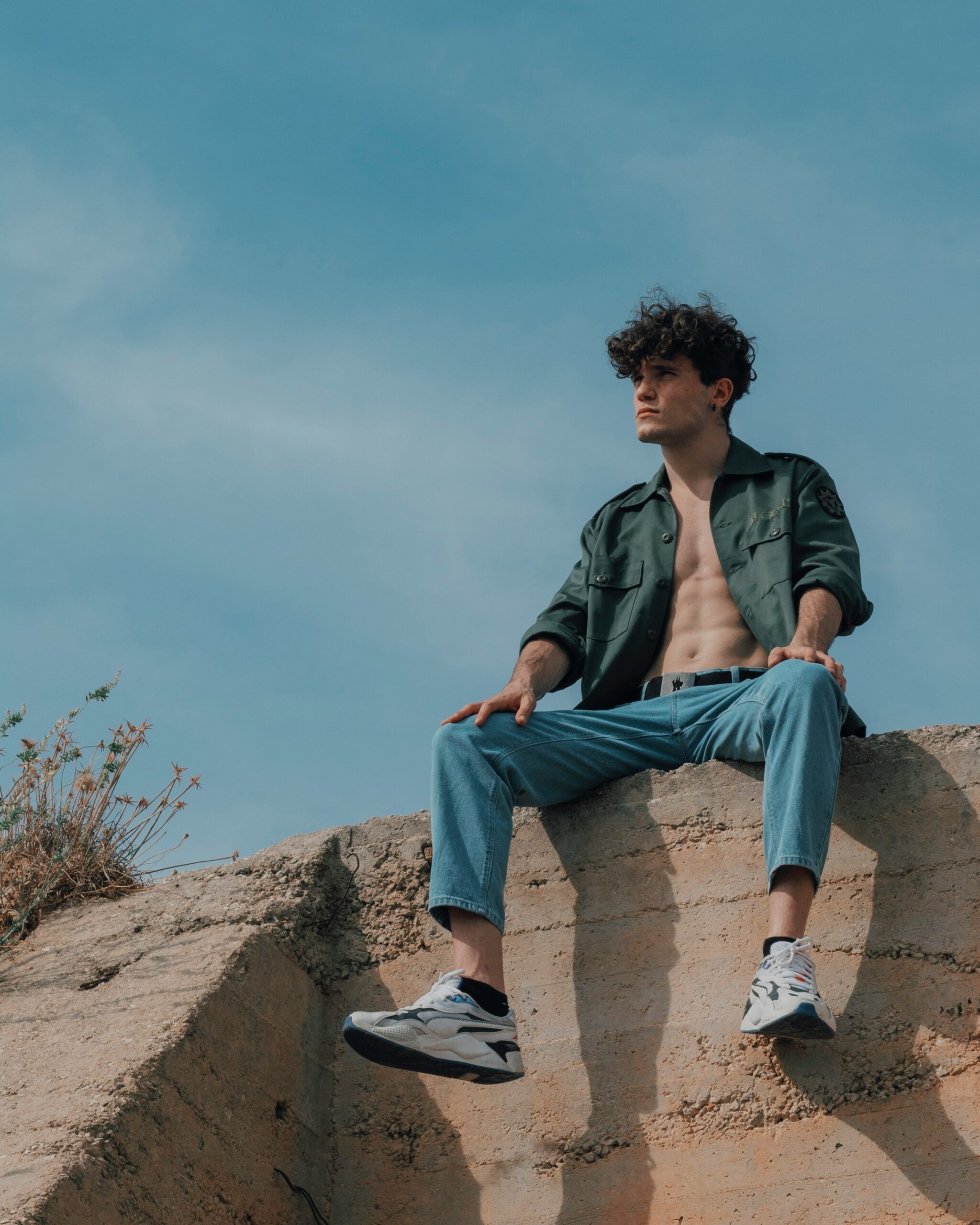 Young man sitting on a rock staring into space